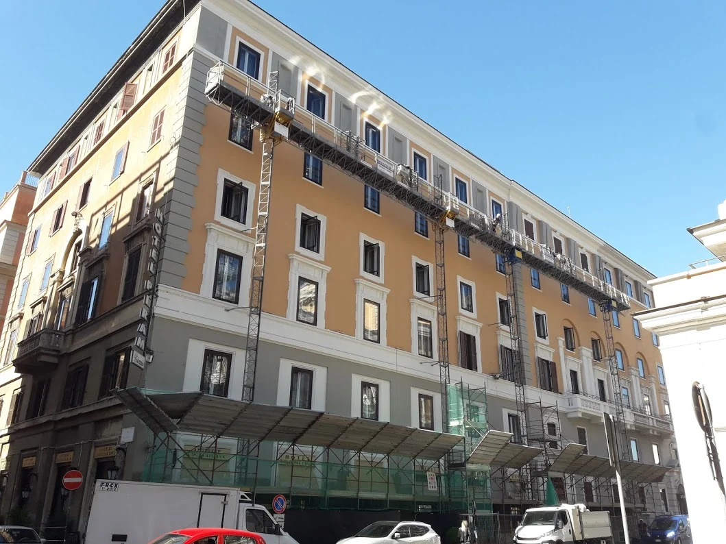 Ponteggi elettrici autosollevanti lungo la facciata del palazzo giallo a Roma